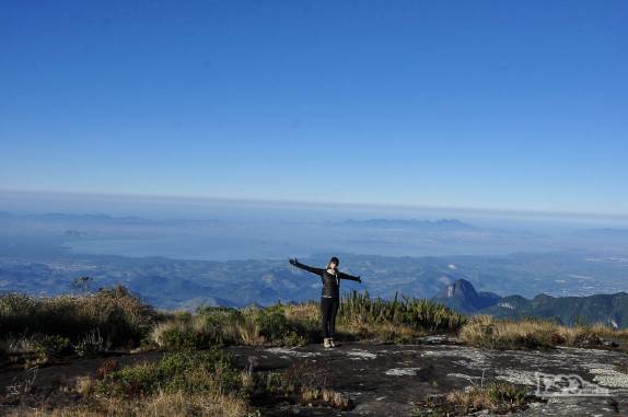 Feliz com mais um dia de céu azul no Parque Nacional da Serra dos Órgãos, no Rio de Janeiro. Ao fundo, a Baía da Guanabara